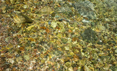 yellow bright lake shoreline transparent water with stones on a bottom 