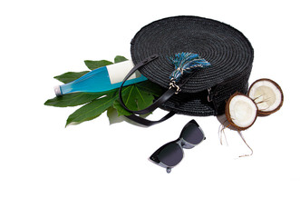 Round rattan bag, sunglasses, half cracked coconut on white