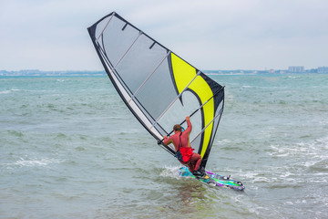 the fat man windsurfer in the red wetsuit with a board very cool rides in windsurf with yellow sail