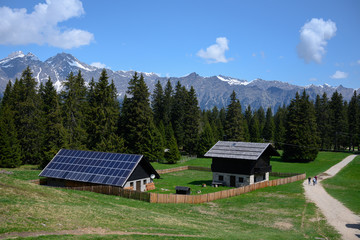 sustainable photovoltaics houses in mountain alps at forest with blue sky