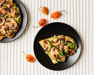 Avocado Toast with Mushrooms On A Black Plate with Light Background, Top View