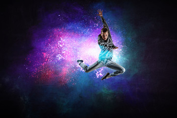 Fototapeta na wymiar Modern female dancer jumping in hoodie with colourful splashes background. Mixed media