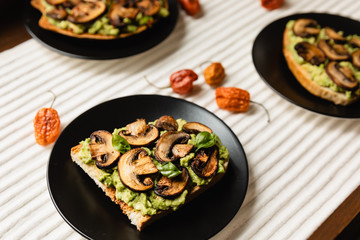 Avocado Toast with Mushrooms On A Black Plate with Light Background