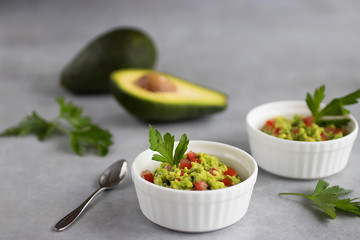 Appetizer of avocado in white bowls over gray background. Guacamole.