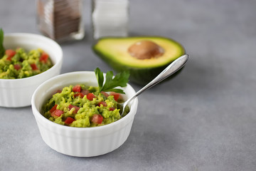 Appetizer of avocado in white bowls over gray background. Guacamole.