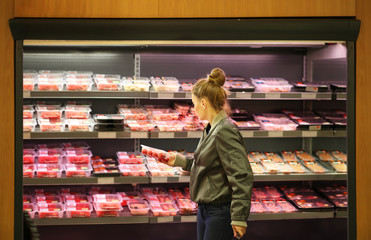 Woman purchasing a packet of meat at the supermarket 