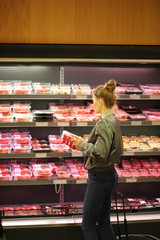 Woman purchasing a packet of meat at the supermarket 