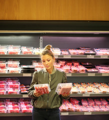 Woman purchasing a packet of meat at the supermarket 