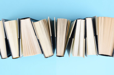 High angle image of a row of books standing on end on a light blue background