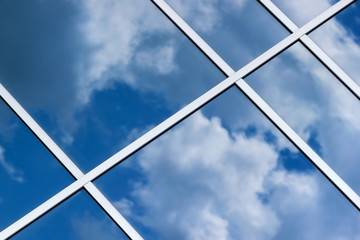 Sky clouds reflection in office building glass window, selective focus