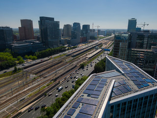 Aerial of modern sustainable office building with solar panels, part of transit oriented development next to train station in Amsterdam Zuidas business district