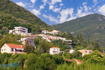 Fototapeta na wymiar Summer vacation in the village. Beautiful summer landscape with a small village on the mountainside on a sunny day. Montenegro, Tivat, Donja Lastva village