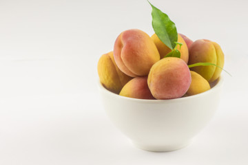 Apricots in a white bowl. Set of apricots isolated on a white background. Ripe apricots with copy space for text.