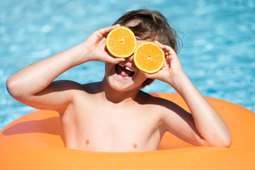 young child smiling in the pool with float and glasses
