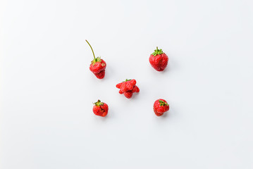 Ugly strawberry on a white background. Ugly food, top view, vertical orientation.