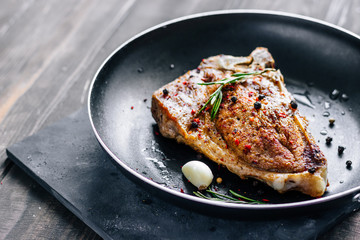 Piece of fried meat with rosemary and garlic in a pan close up