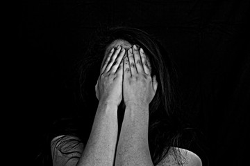 Stopping violence against women, Woman covering her face in fear of domestic violence, Dark tone