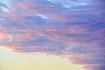 The clouds in the blue sky are illuminated by the orange setting sun. Natural background.