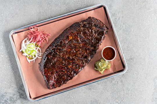 Barbecue ribs on a metal tray with pickled vegetables