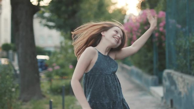 Funny young girl in green dress dancing, moving to beat in street, spinning. Footage of amazing teenager having fun. Alone. Crazy mood.