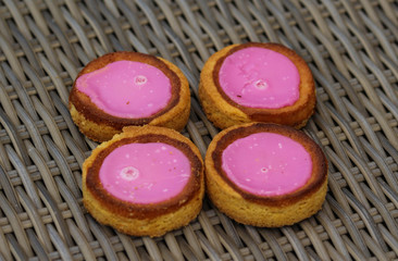 Self made Dutch Butter Cake (Boterkoek) cookie with pink glaze, fresh baked from the oven. Displayed on wooden background