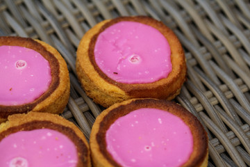 Self made Dutch Butter Cake (Boterkoek) cookie with pink glaze, fresh baked from the oven. Displayed on wooden background