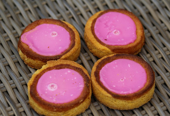 Self made Dutch Butter Cake (Boterkoek) cookie with pink glaze, fresh baked from the oven. Displayed on wooden background