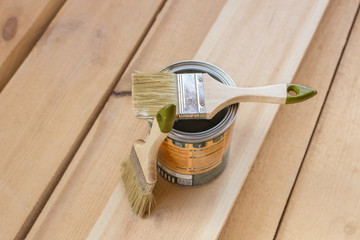 Brushes for painting and empty paint cans on wooden background.
