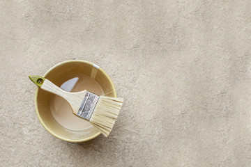 Brush for painting on empty paint can on concrete background. Copy space for design or text.