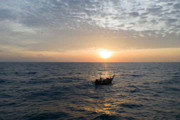 Aerial drone view of sea with drifting fishing boat over amazing sunset with cloudy sky © stryjek