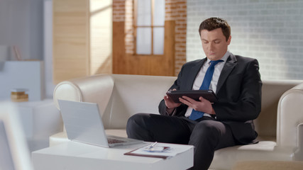 Well-dressed man using tablet in office, modern technologies to manage business