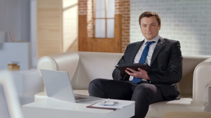 Young man in suit using tablet in office, modern technologies to manage business