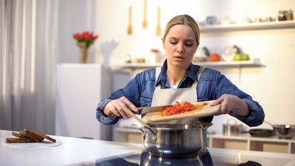 Young beautiful woman unhappy with cooking in kitchen, bored and tired of chores