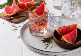 Grapefruit cocktail with rosemary on white wooden table