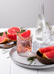 Grapefruit cocktail with rosemary on white wooden table