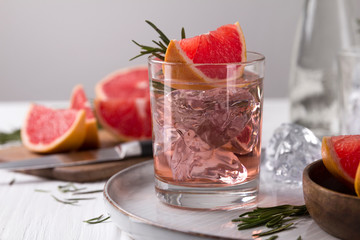 Grapefruit cocktail with rosemary on white wooden table