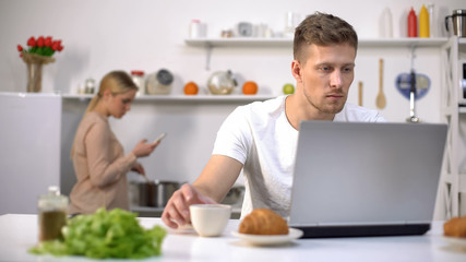 Couple using gadgets in kitchen, ignoring live communication, addiction concept