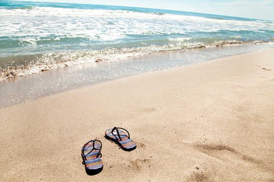Summer holiday beach background with flip flops on a tropical beach. Slippers from a sand on a beach, relax concept