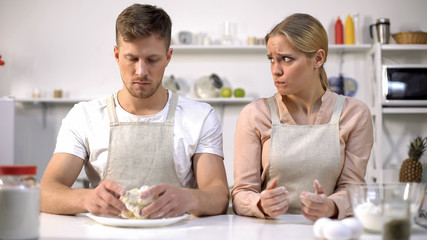 Male holding raw dough, wife looking awkwardly on husband, bad cook, problem