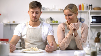 Funny couple looking at raw dough, bad cookers, cooking courses for amateurs