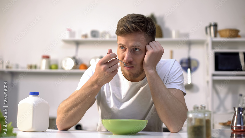 Wall mural male eating breakfast and thinking about work, easy meal day beginning, food