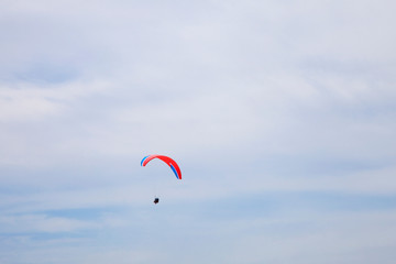 People gliding using a parachute on the background of the blue sky