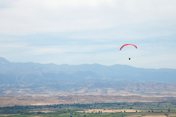People gliding using a parachute on the background of the blue sky