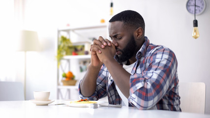 African-American man praying before lunch, thanking God for meal, religion