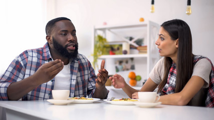 Fototapeta na wymiar Annoyed multiracial couple quarreling during lunch, family relations, conflict