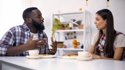Worried multiethnic couple arguing during lunch at home, relationship problems