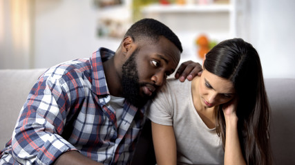 Black husband calming and supporting sad wife, health problems, miscarriage