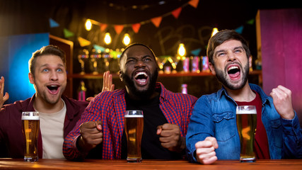 Multiracial male friends supporting favorite football team in bar, results time