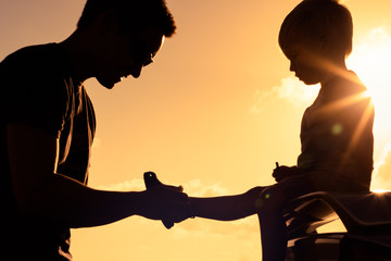 Father helping child put on shoes. Happy father son moment. 