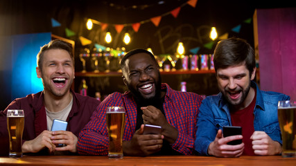 Happy multiethnic friends celebrating team victory, checking results online